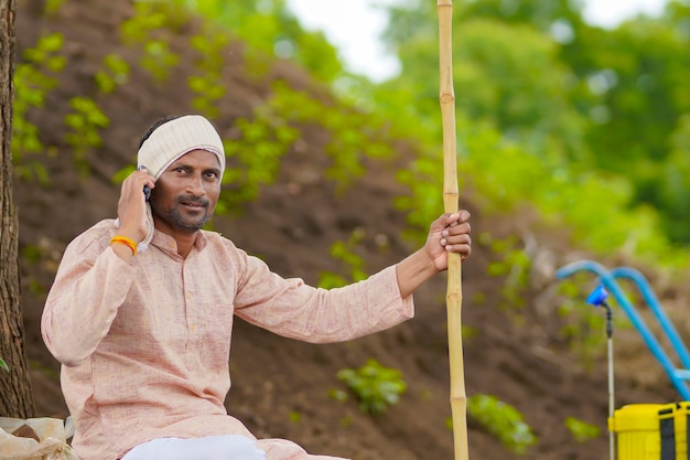 Contadino indiano che parla al telefono cellulare al campo agricolo