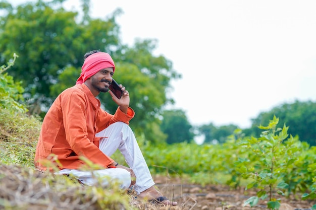 Indian farmer talking on smartphone at agriculture field
