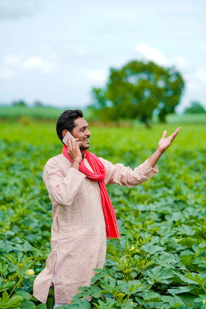 Indian farmer talking on smartphone at agriculture field.