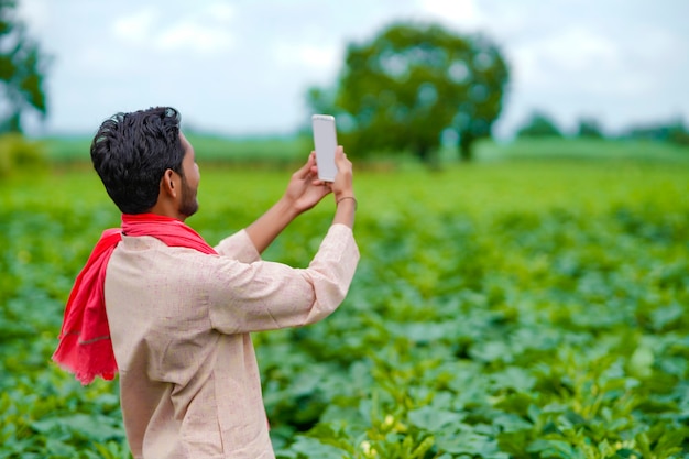 Indian farmer using smartphone at agriculture field.