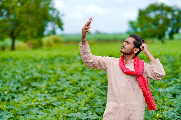 Indian farmer using smartphone at agriculture field.