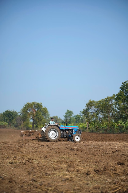 Photo indian farmer working with tractor in agriculture field.