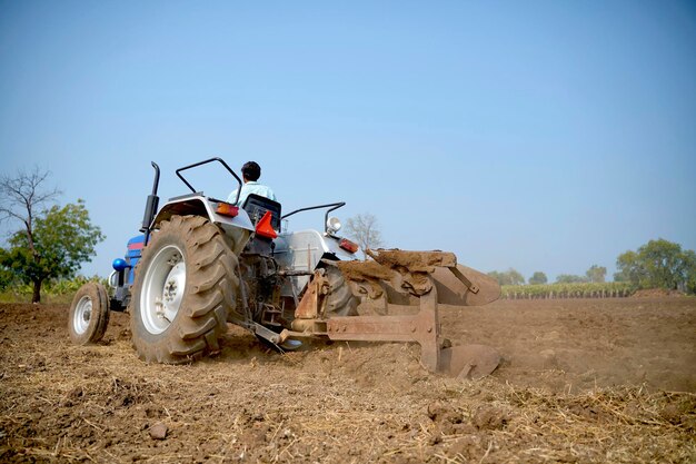 Indian farmer working with tractor in agriculture field.