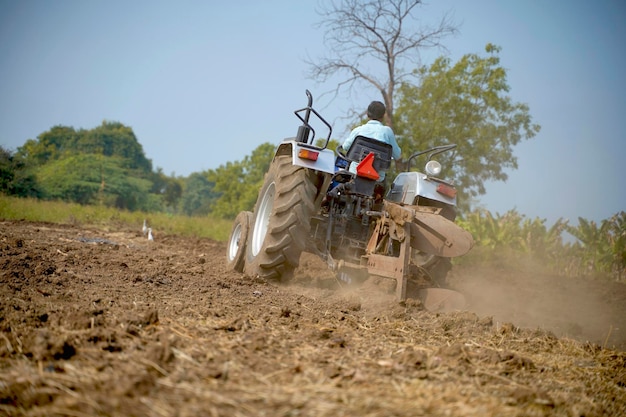 Индийский фермер работает с трактором в сельском хозяйстве.