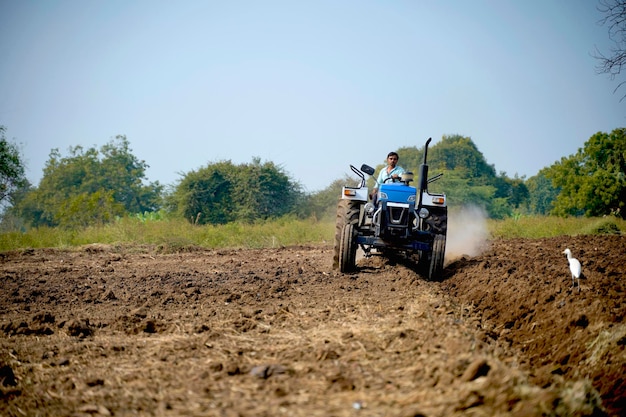 Indian farmer working with tractor in agriculture field.