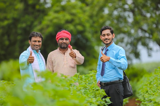 Indian farmers showing thumps up with banker or agronomist at agriculture field.