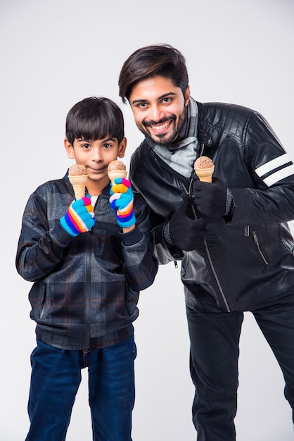 Indian Father and Son eating ice Cream in warm clothes on white background