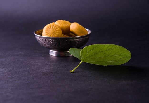 인도 축제 dussehra, 노란색 배경, 인사말 카드에 은색 그릇에 전통적인 인도 과자 pedha와 황금 잎을 보여주는