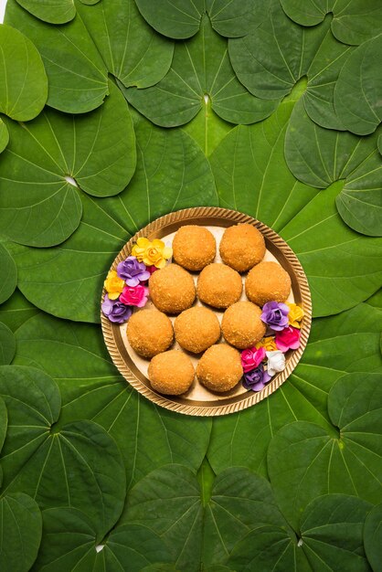 Indian Festival Dussehra, symbolic Golden or Piliostigma leaf or Bauhinia racemosa also known as Apta patti, arranged in circular pattern with Bundi or motichoor laddu served in plate at centre