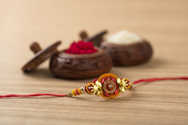 Indian festival: Raksha Bandhan background with an elegant Rakhi, Rice Grains and Kumkum