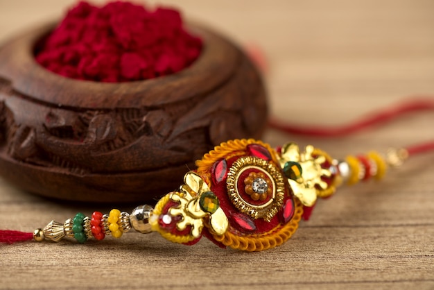 Indian festival: Raksha Bandhan background with an elegant Rakhi, Rice Grains and Kumkum