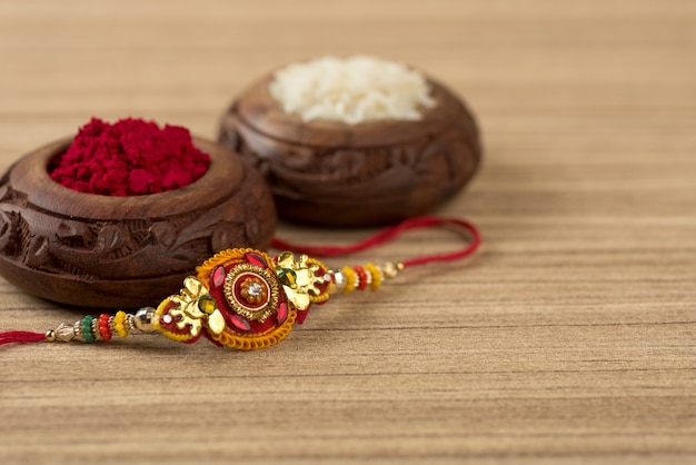 Indian festival: Raksha Bandhan background with an elegant Rakhi, Rice Grains and Kumkum