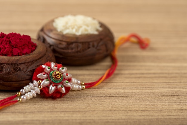 Indian festival: Raksha Bandhan background with an elegant Rakhi, Rice Grains and Kumkum