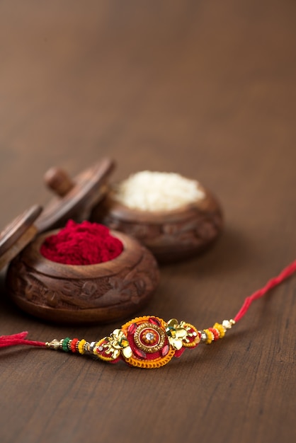 Indian festival: Raksha Bandhan background with an elegant Rakhi, Rice Grains and Kumkum