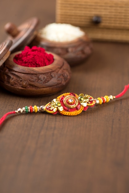 Indian festival: Raksha Bandhan background with an elegant Rakhi, Rice Grains and Kumkum