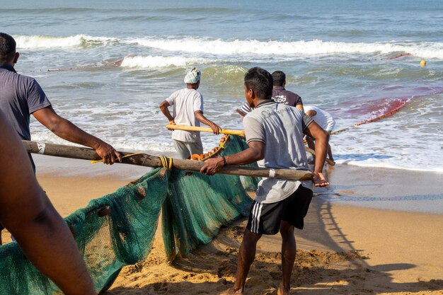 写真 インドの朝に魚を捕まえて網を引くインドの漁師たち