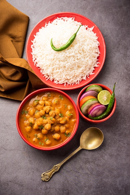 Indian food chole chawal or spicy Chickpea curry with plain rice served with green salad. selective focus