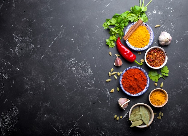 写真 インド料理の背景。伝統的なインドのスパイスと食材。カレー、ターメリック、カルダモン、ニンニク、コショウ、新鮮なコリアンダー、シナモン。エキゾチックな食事の準備。上面図、テキスト用のスペース