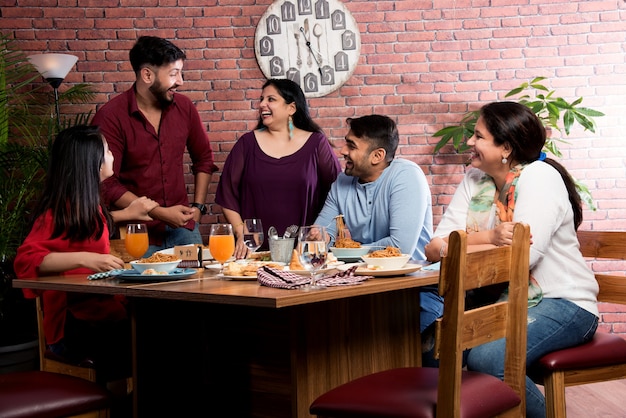 インド人の友人がレストランで食事や食事をしています。集まり、再会、またはお祝いのパーティーに直面しているアジアの人々。コーヒーショップのお祝いの友情の一体感の概念