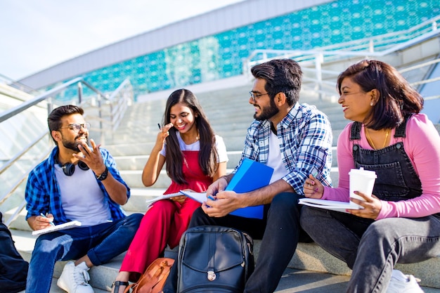 Indian friends sitting on stairs outdoors with copybooks