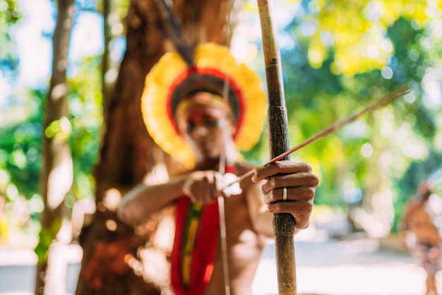 Indian from the PataxÃ³ tribe using a bow and arrow. Brazilian Indian with feather headdress and necklace
