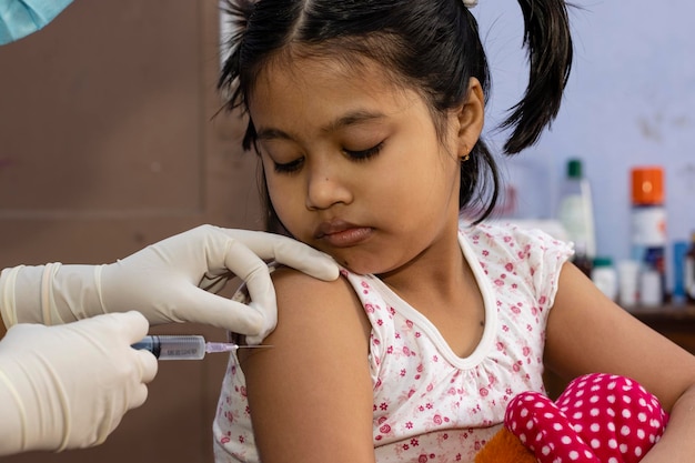 Photo an indian girl child looks at the needle during vaccination