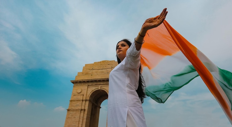 फोटो एक भारतीय लड़की इंडिया गेट के सामने तिरंगे के साथ लहरा रही है