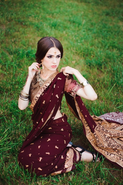 Индийская девушка с восточными украшениями и макияжа хной на руку. Брюнетка индусской модели девушка с индийскими драгоценностями