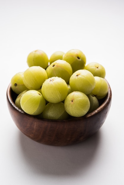 Indian gooseberry or Amla (Phyllanthus emblica) in a cane basket over colourful or wooden surface, selective focus