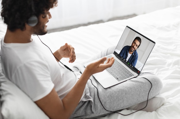 Photo indian guy having video call with his friend using laptop