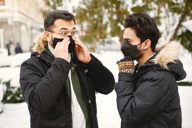 Indian guys in masks. Men on street in winter. Boys wear masks.