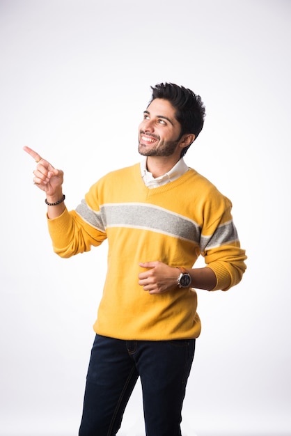 Indian handsome man wears winter wear or woolen sweater, presenting or showing. Standing against white background