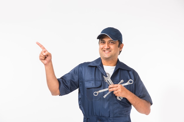 Indian happy auto mechanic in blue suit and cap holding spanner tool