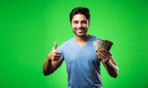 Индийский счастливый человек с денежным вентилятором, стоящий изолированно от зеленого экрана цветности