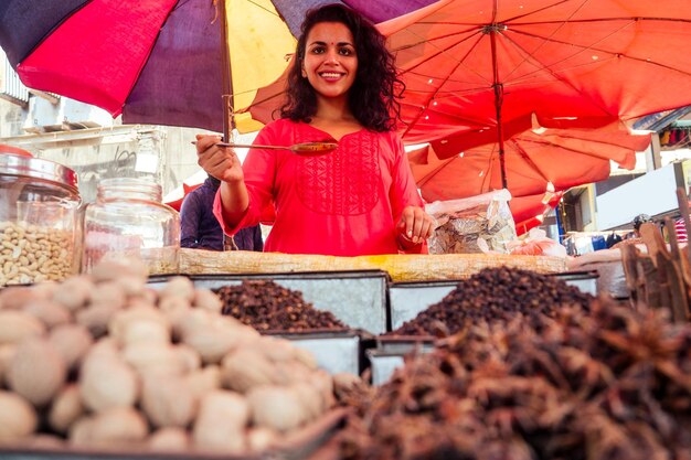 ゴアのバザールでスパイスを売るインドの幸せな女性