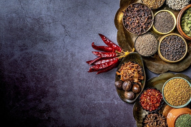 Indian herbs and spices in different bowl condiments top view dark background