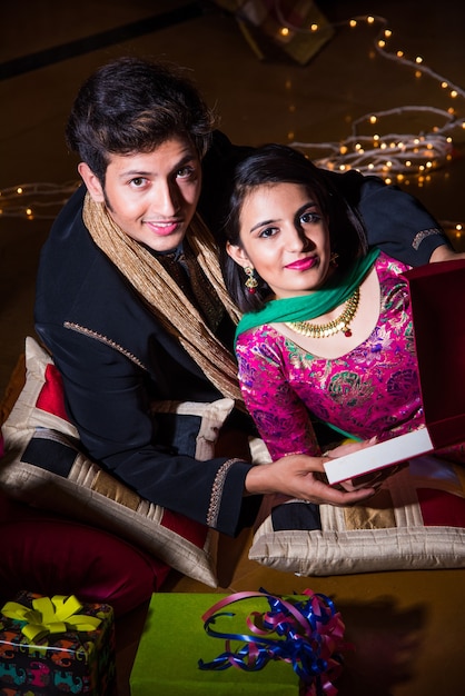 Indian husband tying or presenting necklace to his beautiful\
wife to celebrate anniversary of diwali festival