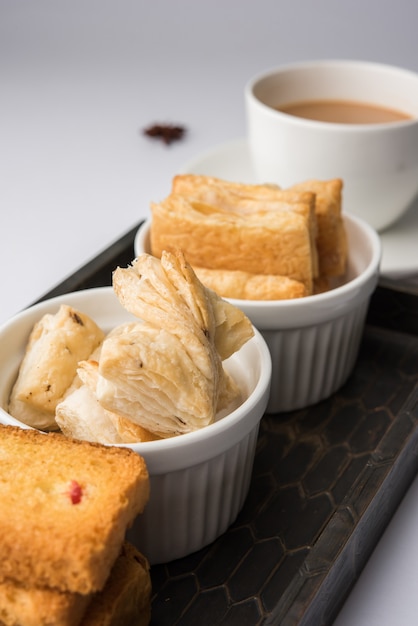 Indian khari or kharee or salty Puff Pastry Snacks and tutti frutti toast, served with indian hot tea, selective focus texture