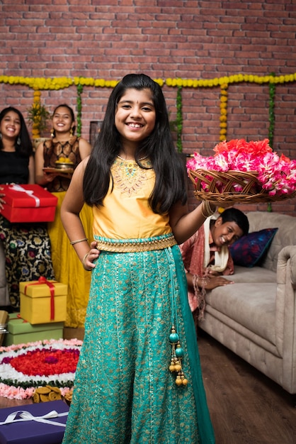 Indian Kids celebrating Diwali, Deepawali, Bhai Dooj or Rakhi or Raksha Bandhan with flower rangoli, gifts, diya