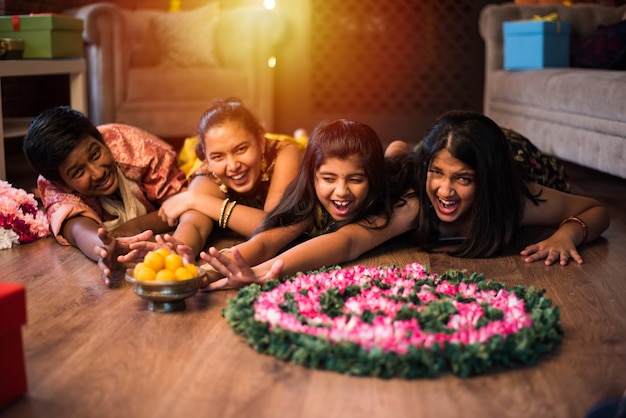 Photo indian kids celebrating diwali, deepawali, bhai dooj or rakhi or raksha bandhan with flower rangoli, gifts, diya