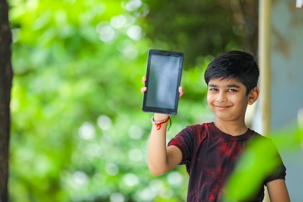 Индийский маленький мальчик, показывающий экран смартфона
