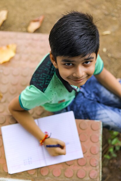 Photo indian little boy writing on note book