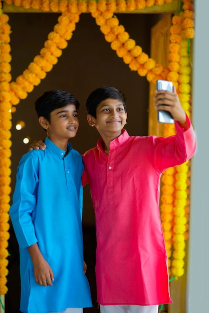 Indian little boys using smartphone and enjoying diwali festival.