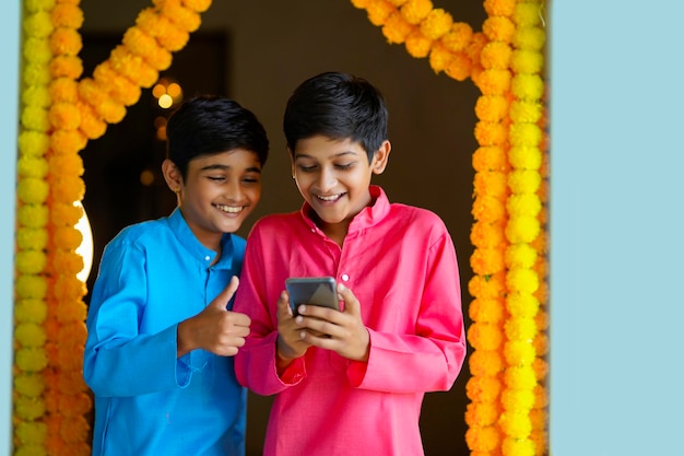 Indian little boys using smartphone and enjoying diwali festival.