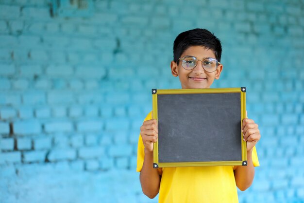 Indian little child showing chalkboard with copy space