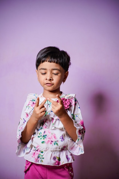 Photo indian little girl doing mathematics by counting fingers at home