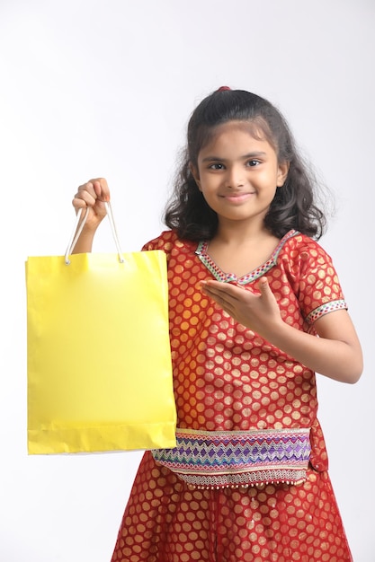 Indian little girl holding shopping bag and giving expression on white background