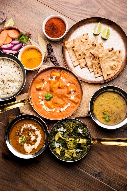 Indian Lunch or Dinner main course food in group includes Paneer Butter Masala, Dal Makhani, Palak Paneer, Roti, Rice etc, Selective focus