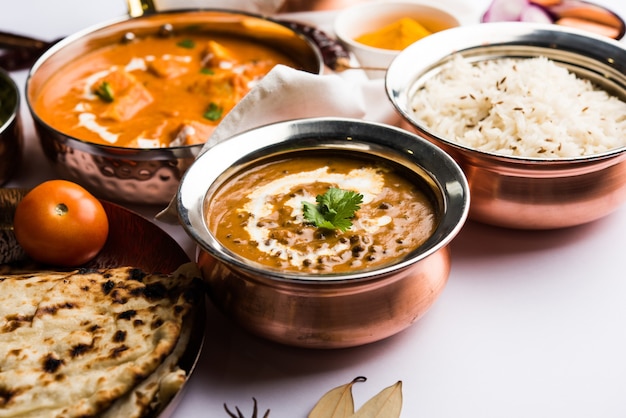 Indian Lunch or Dinner main course food in group includes Paneer Butter Masala, Dal Makhani, Palak Paneer, Roti, Rice etc, Selective focus