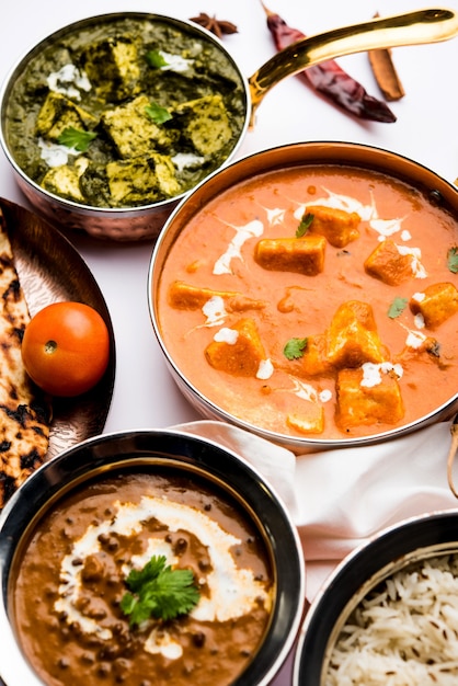 Indian Lunch or Dinner main course food in group includes Paneer Butter Masala, Dal Makhani, Palak Paneer, Roti, Rice etc, Selective focus